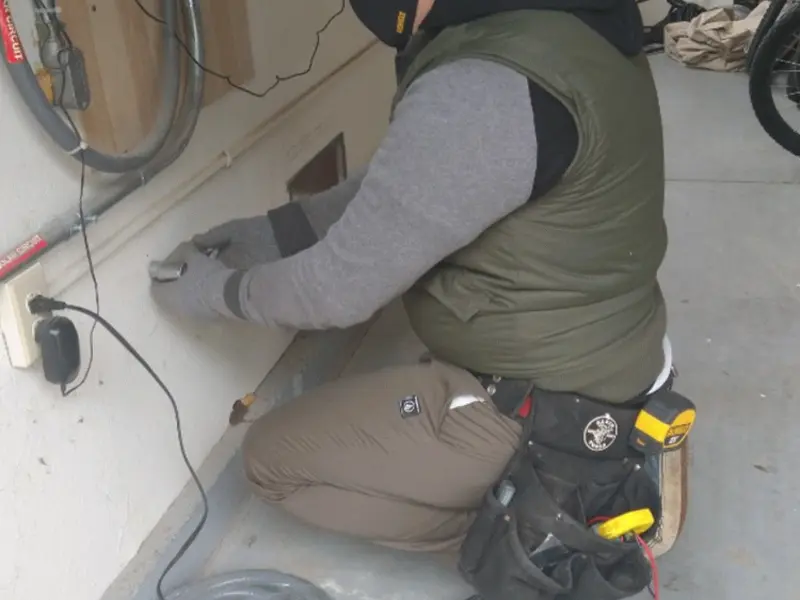 Electrician performing outlet wiring in a San Diego garage